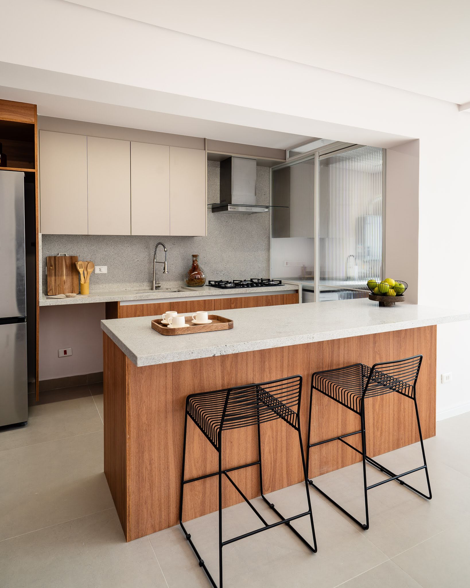 Cozinha com ilha de forno embutido, bancada com cooktop e vista do hall de entrada — Bela Cintra 201