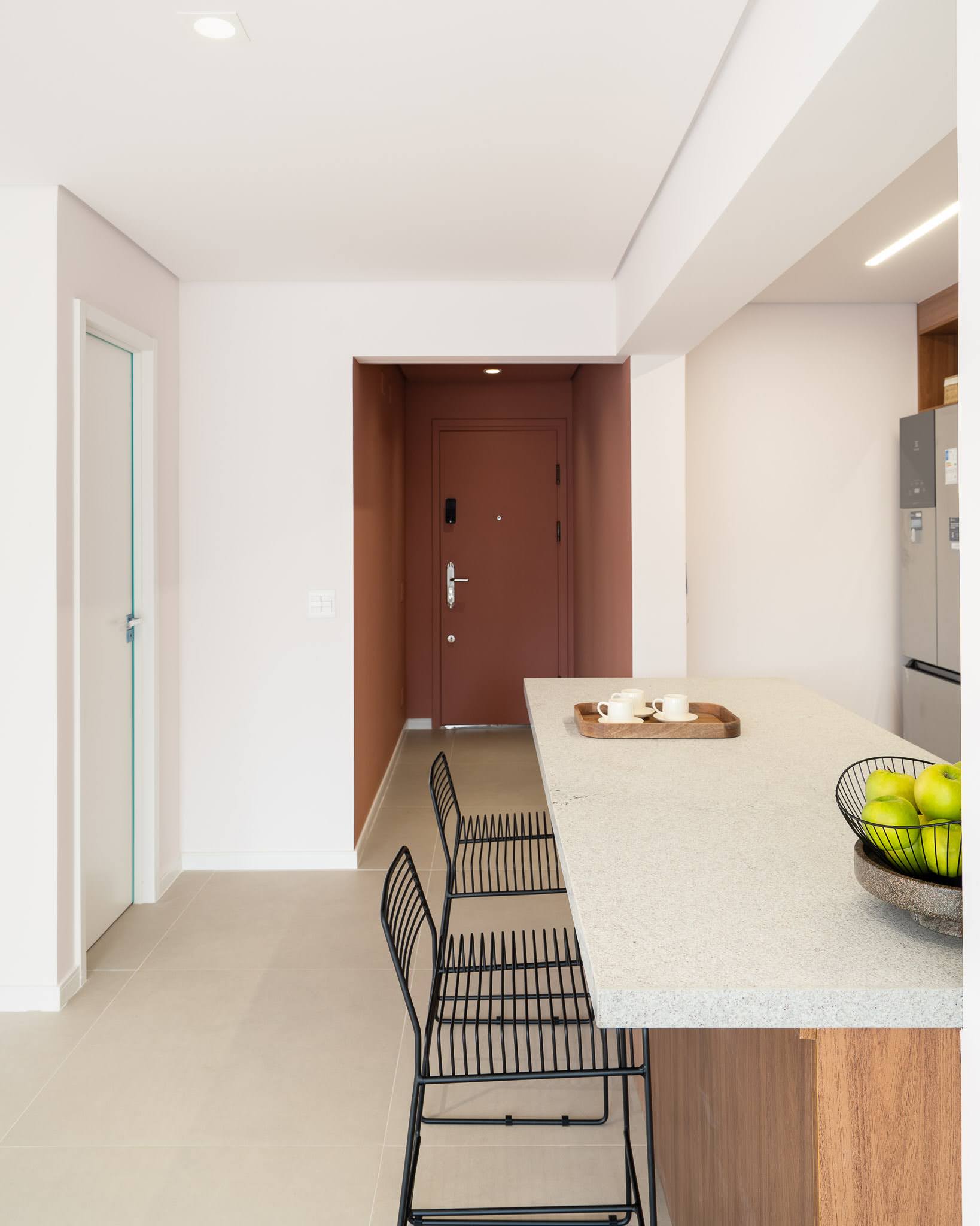 Ilha da cozinha com banquetas e hall de entrada ao fundo — Bela Cintra 201